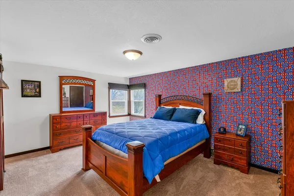 a bedroom with a bed and a dresser next to a window