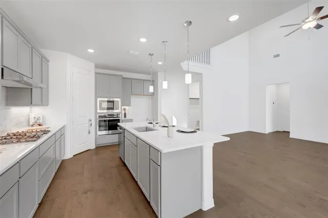 a large kitchen with stainless steel appliances kitchen island a large counter top a stove a chimney a sink and a refrigerator