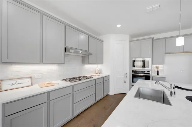 a kitchen with granite countertop a sink a stove and cabinets