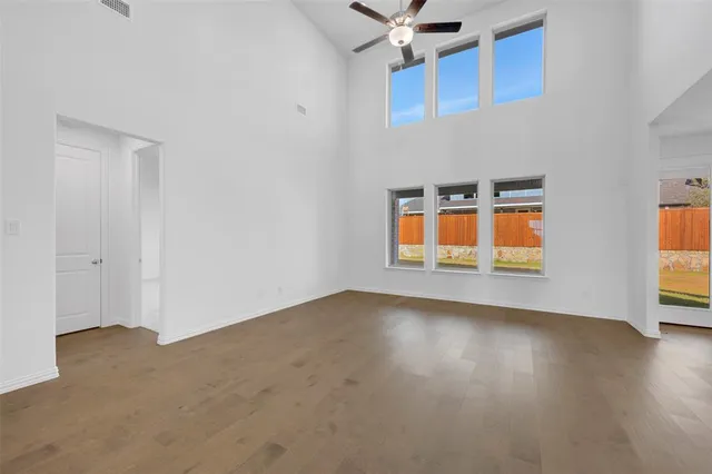 an empty room with wooden floor cabinet and windows