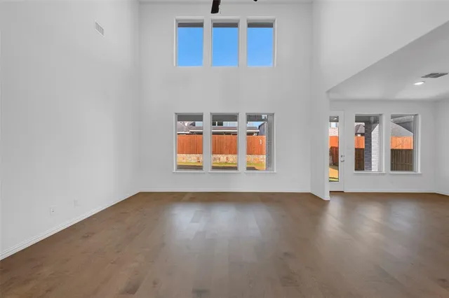 a view of an empty room with window and wooden floor