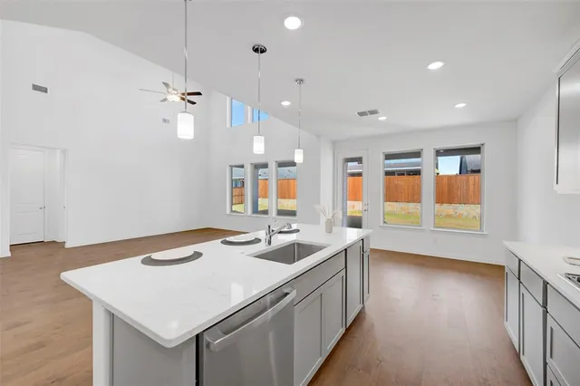 a hall with kitchen island a sink dishwasher a stove and a dining table with wooden floor