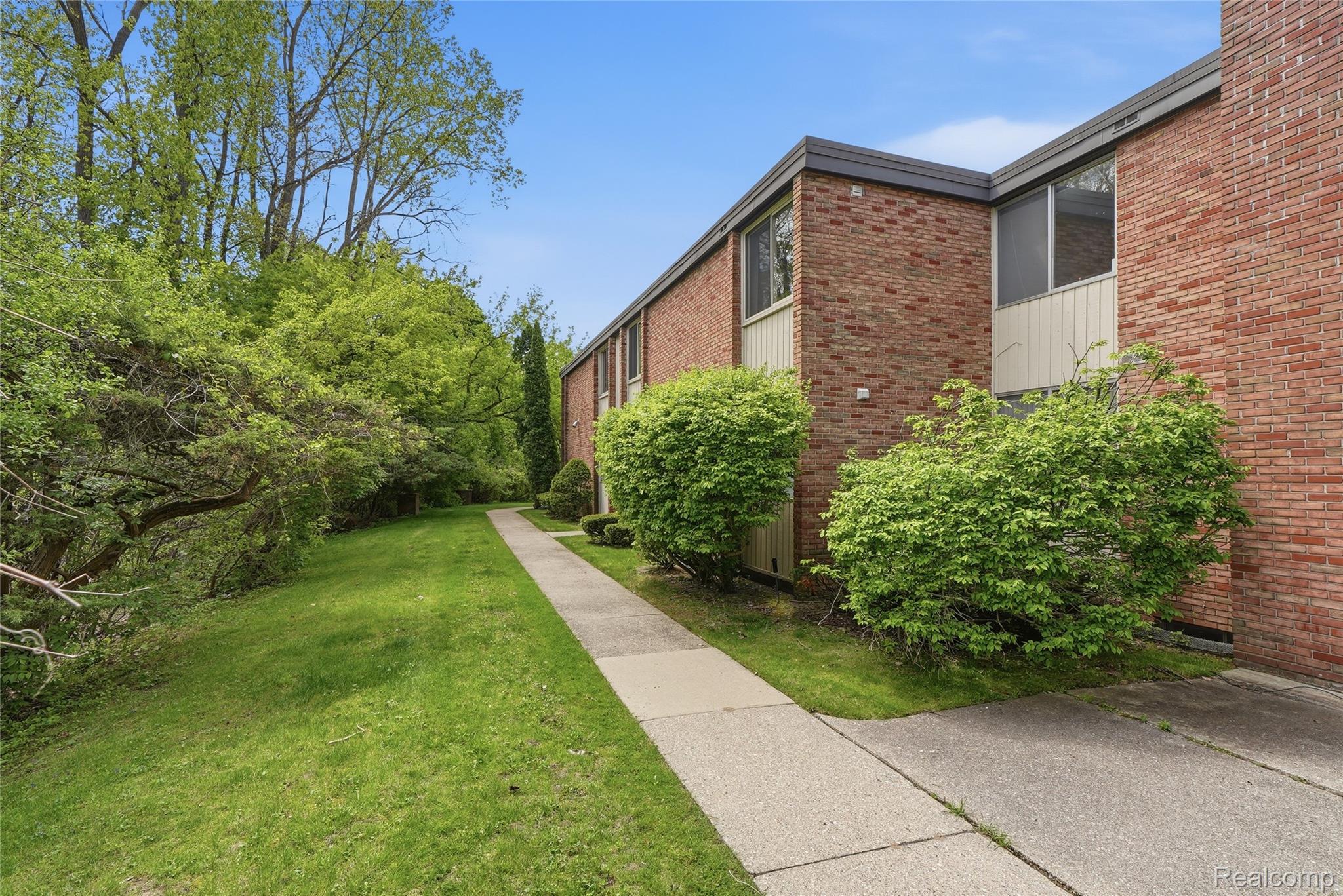 4041 West Maple Road, Unit E203 Bloomfield Hills, MI 48301 - Photo 24 of 25 View of home's exterior featuring a yard and brick siding