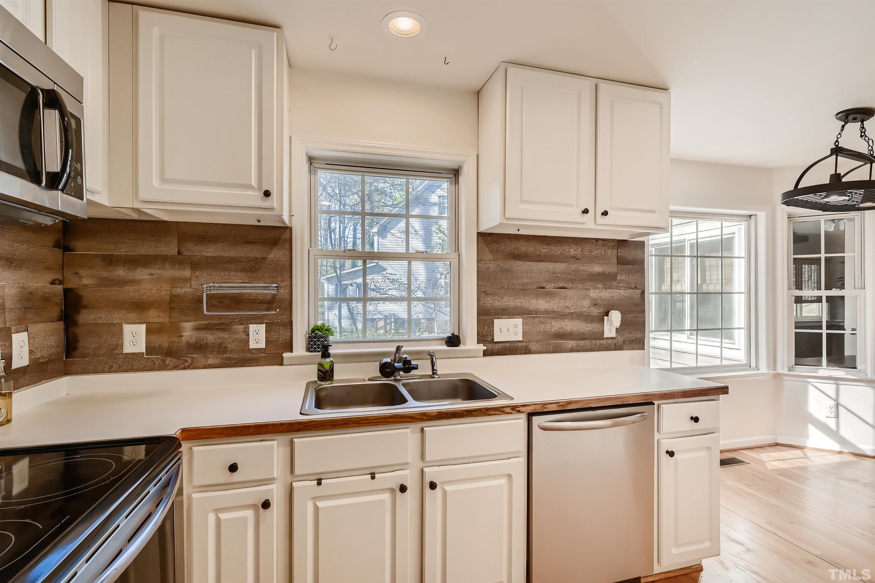 1705 Reynolda Court Raleigh, NC 27603 - Photo 11 of 28 a kitchen with stainless steel appliances a sink a stove and white cabinets with wooden floor