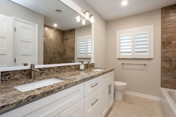 a bathroom with a granite countertop sink and a mirror