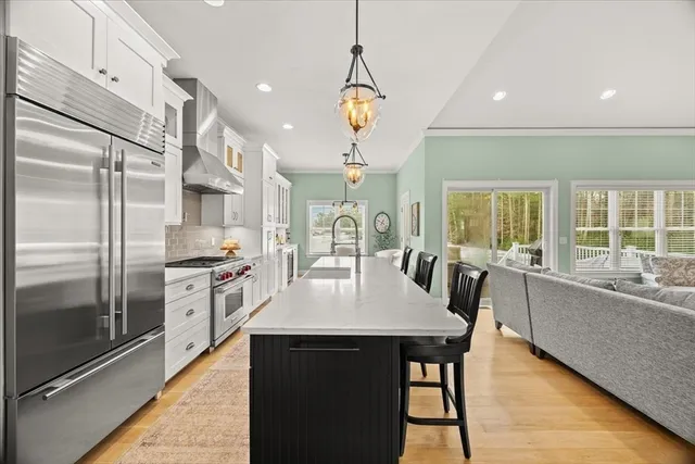 a large kitchen with granite countertop a stove a sink dishwasher a refrigerator and a dining table with wooden floor