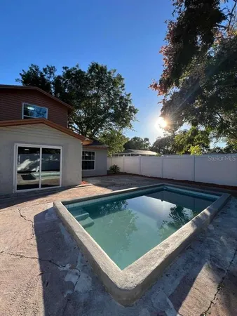 a view of swimming pool on a sunny day with lawn chairs