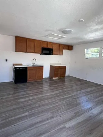 a view of kitchen with stainless steel appliances wooden floor and chair