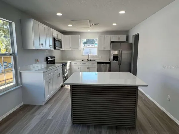 a kitchen with kitchen island a sink stainless steel appliances and cabinets