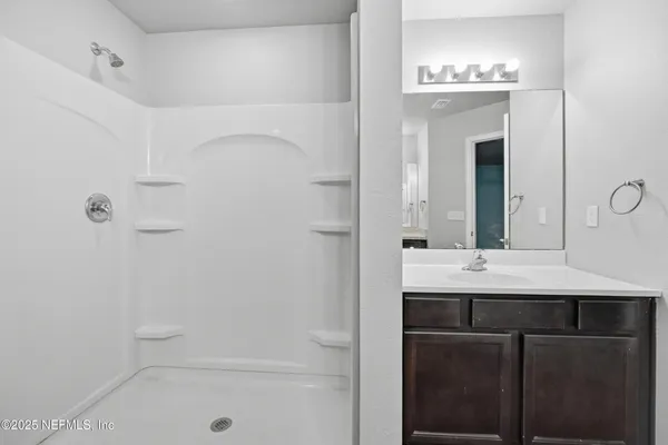 a bathroom with a shower a sink and a mirror