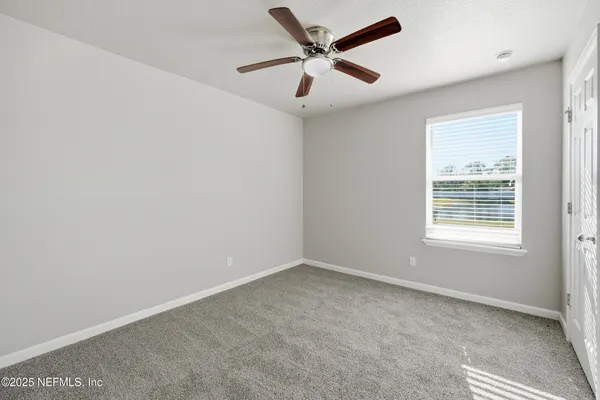 an empty room with a window and a fan
