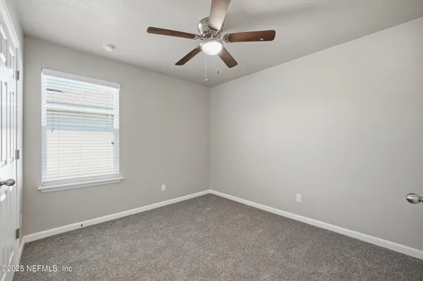 an empty room with windows and fan