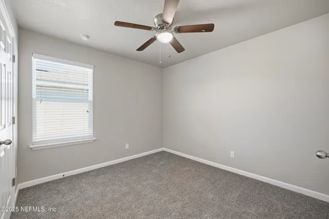 an empty room with windows and fan
