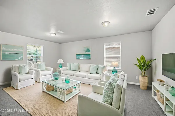a living room with furniture a flat screen tv and a potted plant