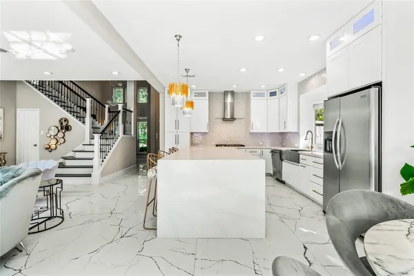a kitchen with stainless steel appliances kitchen island granite countertop a refrigerator a sink a stove and white cabinets