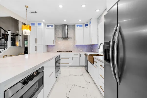 a large kitchen with stainless steel appliances kitchen island granite countertop a refrigerator a stove and a sink