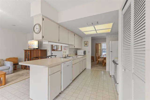 a large white kitchen with a sink and dishwasher a stove with wooden floors