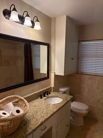 a bathroom with a granite countertop sink and a toilet