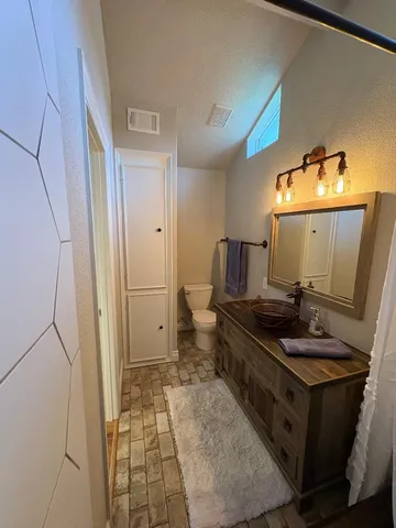 a bathroom with a granite countertop sink a toilet and a mirror