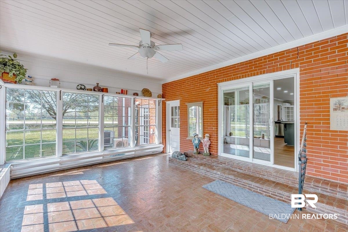 14160 Moffett Road Wilmer, AL 36587 - Photo 10 of 75 Unfurnished sunroom with brick floor, a ceiling fan, and brick wall