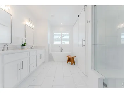 a spacious bathroom with a double vanity sink a mirror and a bathtub