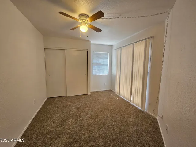 an empty room with a chandelier fan and closet