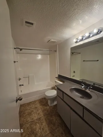 a bathroom with a granite countertop sink a toilet a mirror and shower