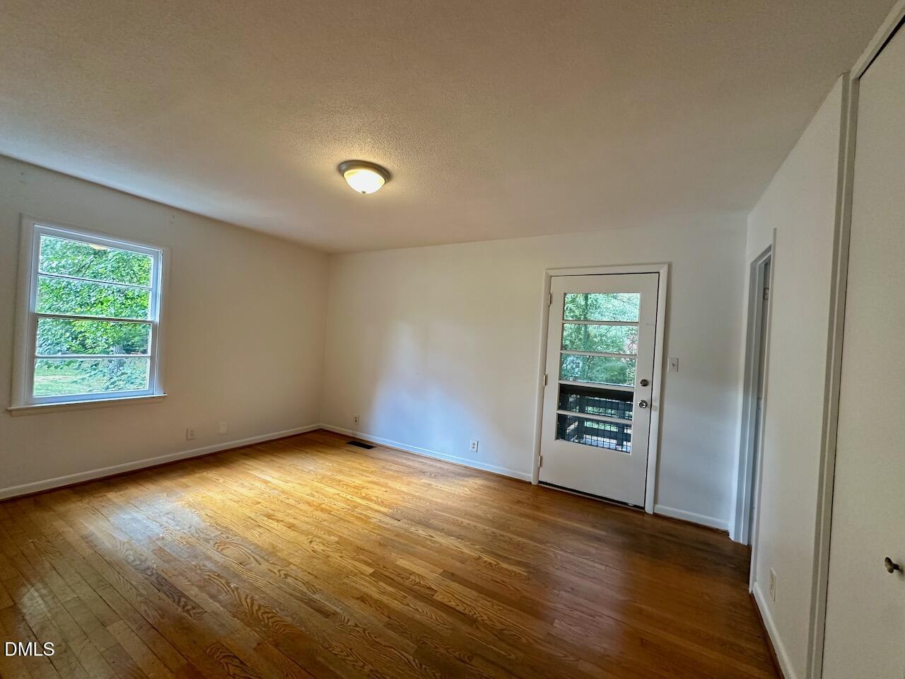 3421 Huntleigh Drive Raleigh, NC 27604 - Photo 12 of 27 an empty room with wooden floor mirror and windows