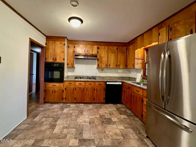 a kitchen with stainless steel appliances granite countertop a refrigerator a stove and a sink