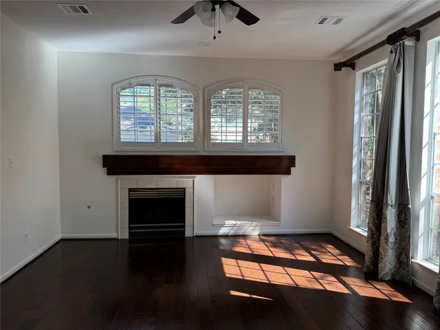 an empty room with windows fireplace and wooden floor