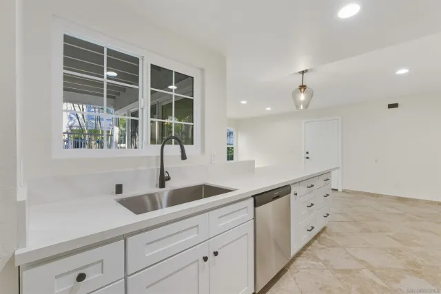 a kitchen with granite countertop a sink and white cabinets