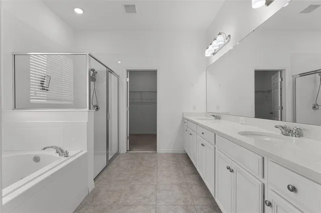 a spacious bathroom with a double vanity sink a mirror and a bathtub