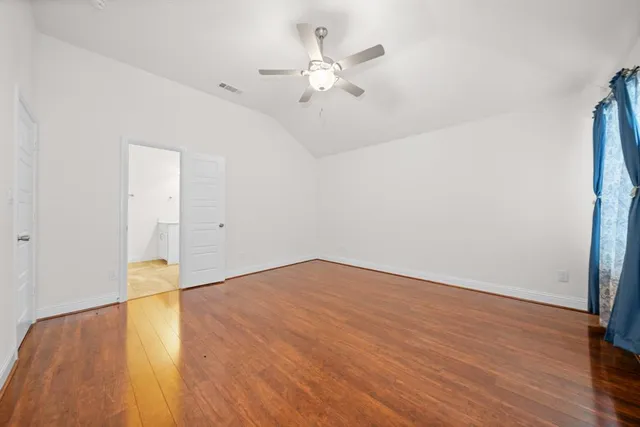 an empty room with wooden floor and ceiling fan