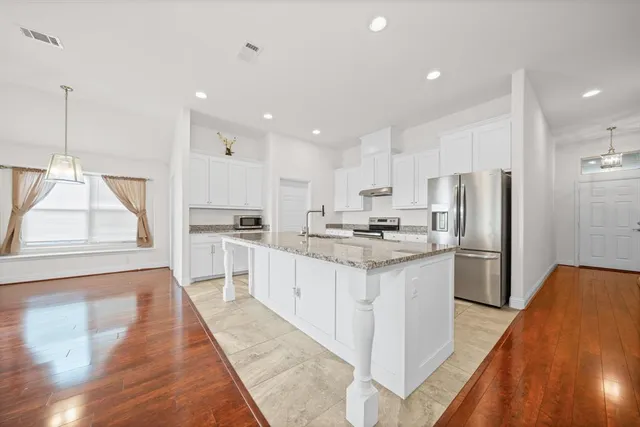 a kitchen with stainless steel appliances granite countertop a refrigerator sink and white cabinets