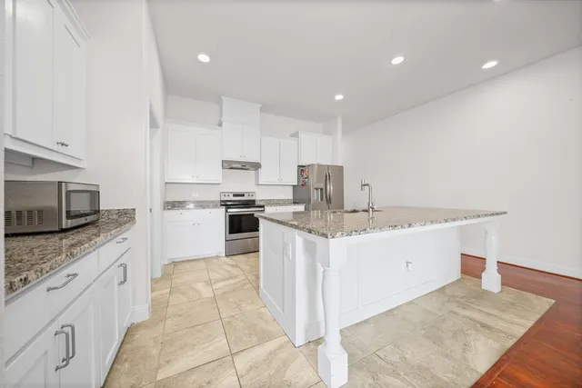 a kitchen with granite countertop a sink stove and refrigerator