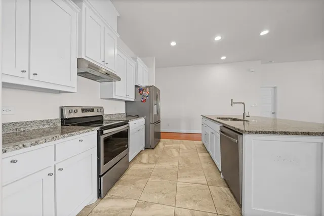 a kitchen with stainless steel appliances granite countertop a stove a sink and a refrigerator