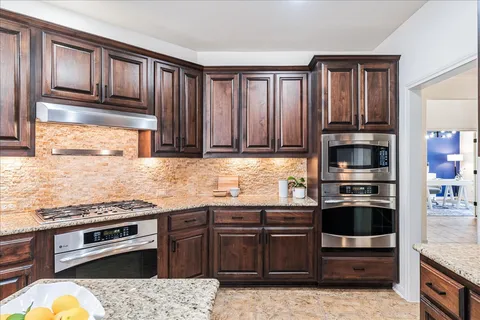 a kitchen with granite countertop wooden cabinets and stainless steel appliances