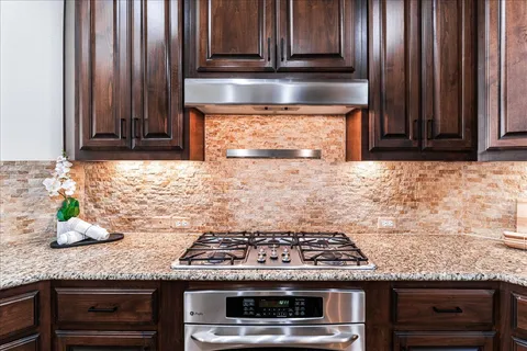 a kitchen with granite countertop a stove wooden cabinets and a counter top space