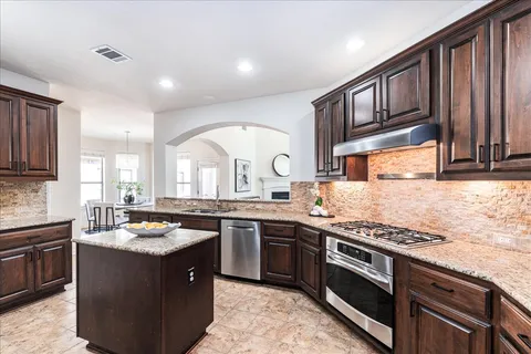 a kitchen with stainless steel appliances granite countertop a stove a sink dishwasher and cabinets with wooden floor