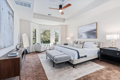 a spacious bedroom with a bed a couch and large window