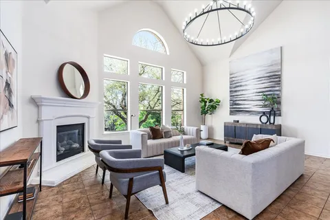a living room with furniture a fireplace a large window and a potted plant