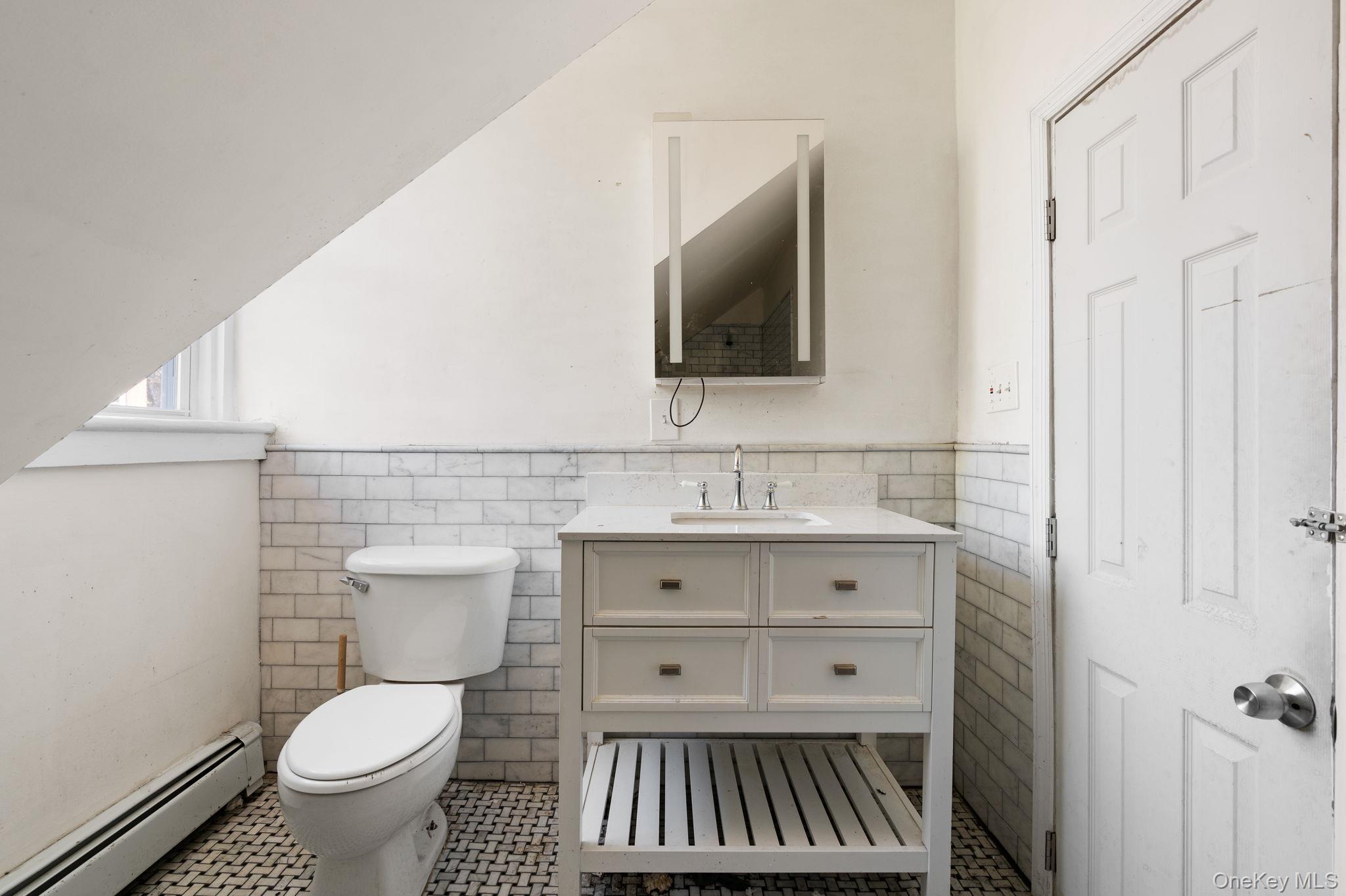 77 Academy Street Poughkeepsie, NY 12601 - Photo 18 of 30 Bathroom featuring baseboard heating, tile walls, vanity, a wainscoted wall, and tile patterned floors