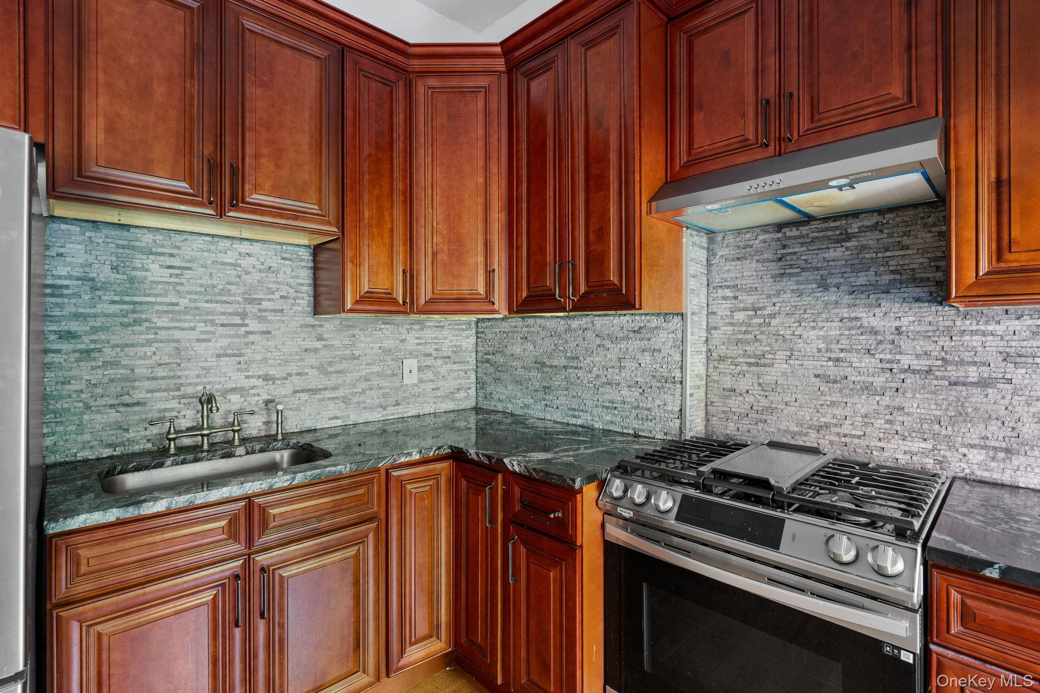 77 Academy Street Poughkeepsie, NY 12601 - Photo 8 of 30 Kitchen featuring stainless steel appliances, under cabinet range hood, backsplash, and dark stone countertops