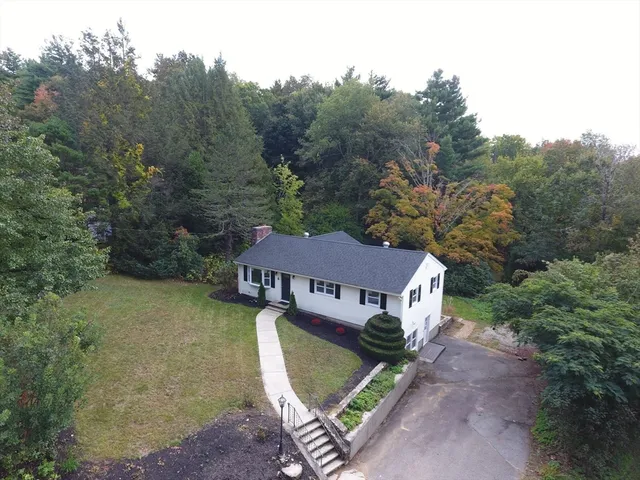 an aerial view of a house with garden space and trees all around