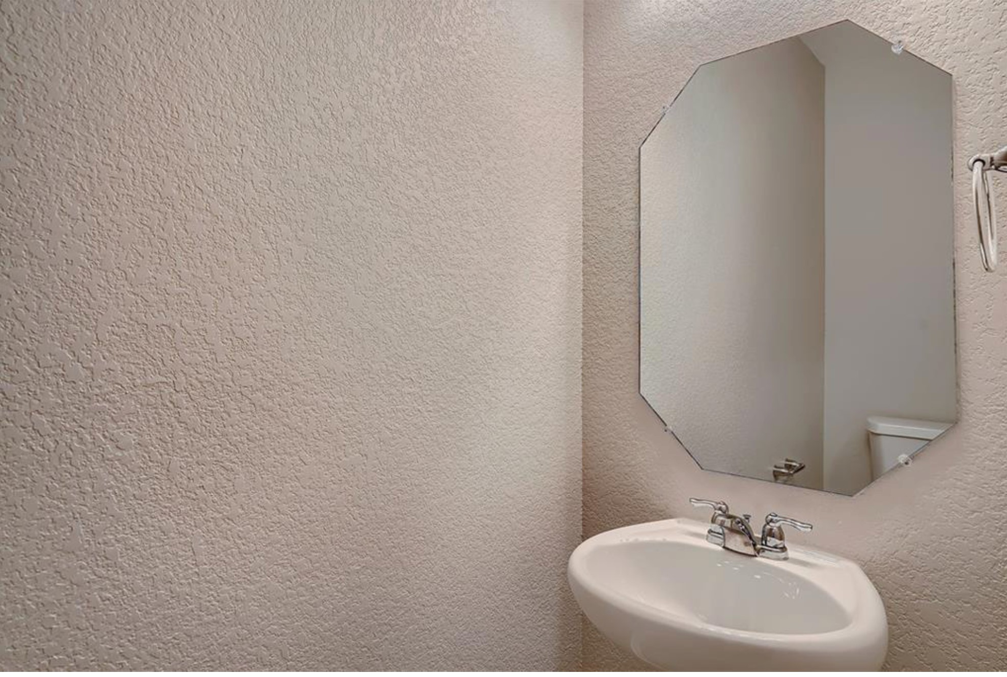304 Cane River Road Pflugerville, TX 78660 - Photo 16 of 31 A compact half bath features a pedestal sink and an octagonal mirror, optimizing space.