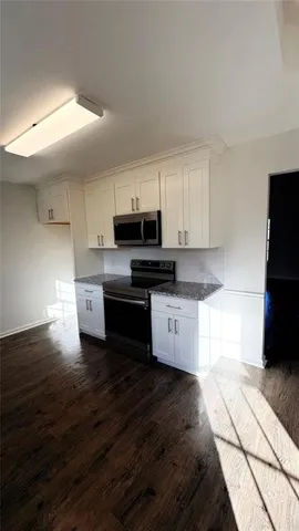 a kitchen with granite countertop a stove a sink and a microwave