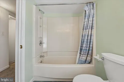 a bathroom with a toilet a sink a mirror a window and vanity
