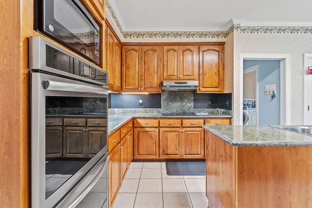 a kitchen with stainless steel appliances granite countertop a stove a sink and a microwave