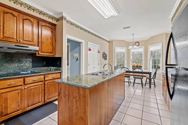 a kitchen with stainless steel appliances granite countertop a refrigerator a sink dishwasher a stove and a dining table with wooden floor
