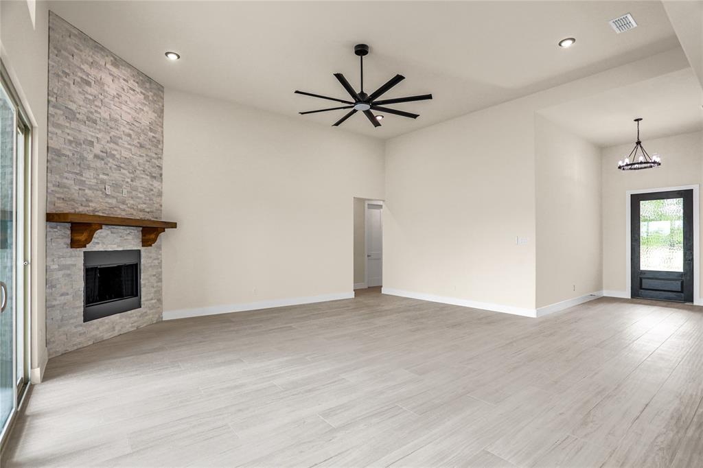 7637 County Road 1052 Celeste, TX 75423 - Photo 13 of 40 Unfurnished living room with a chandelier, a fireplace, light wood-style flooring, ceiling fan, and recessed lighting